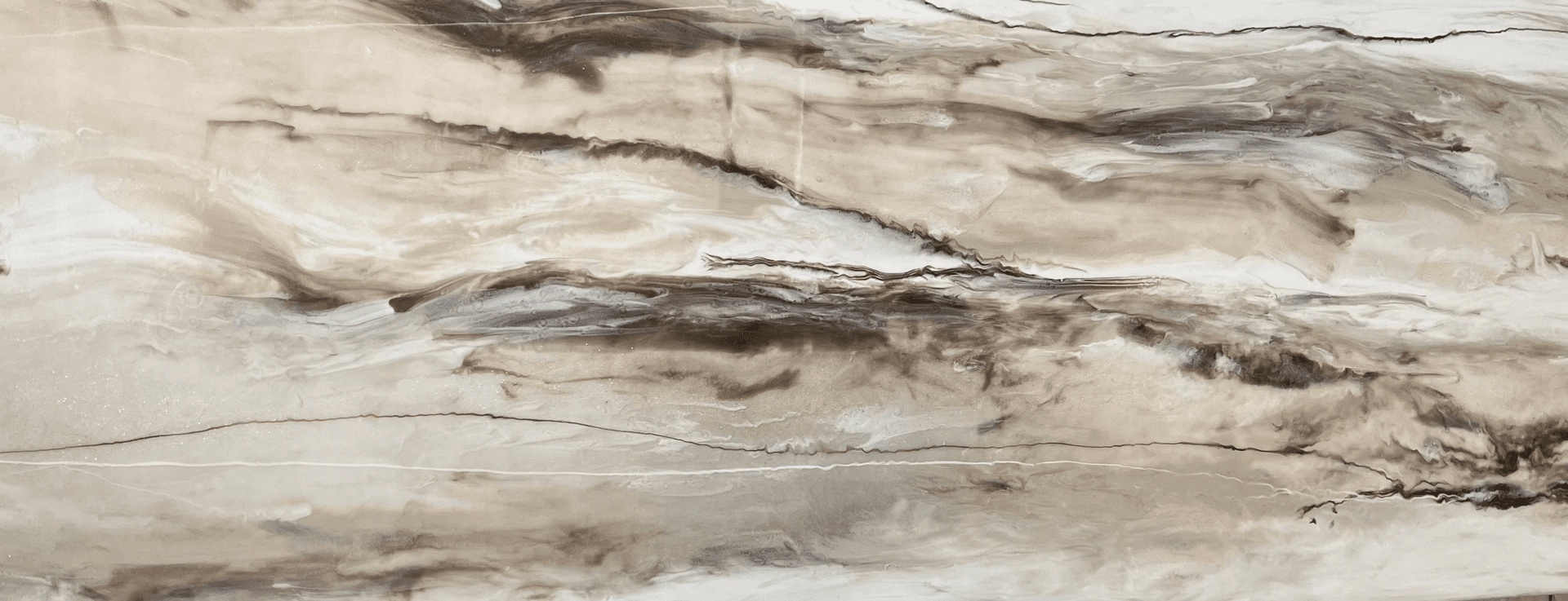 Marble slab with swirling patterns in beige, brown, and cream tones, creating a sleek, elegant appearance with a natural, earthy feel.